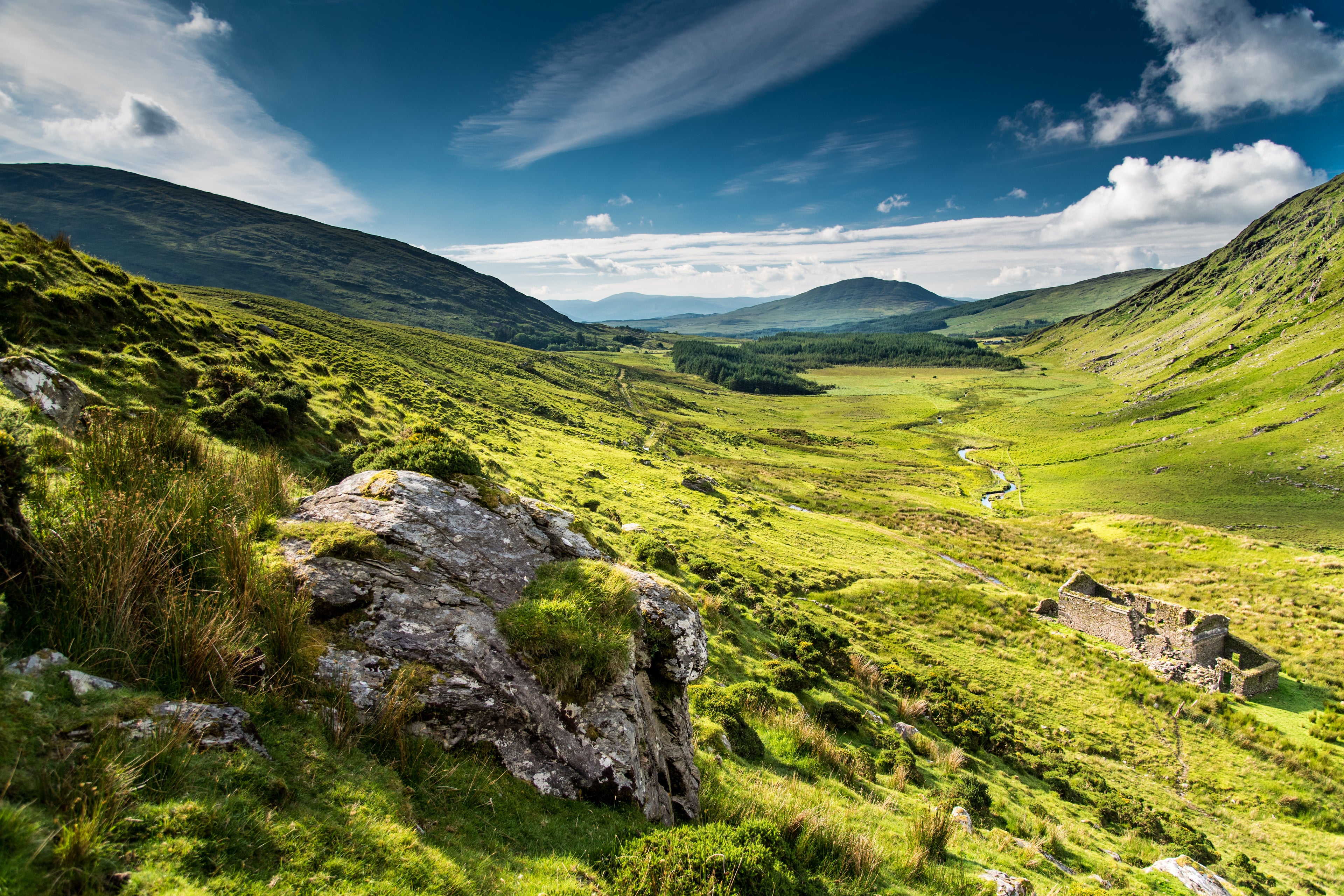 Scenic view of a green valley with mountains under a blue sky.